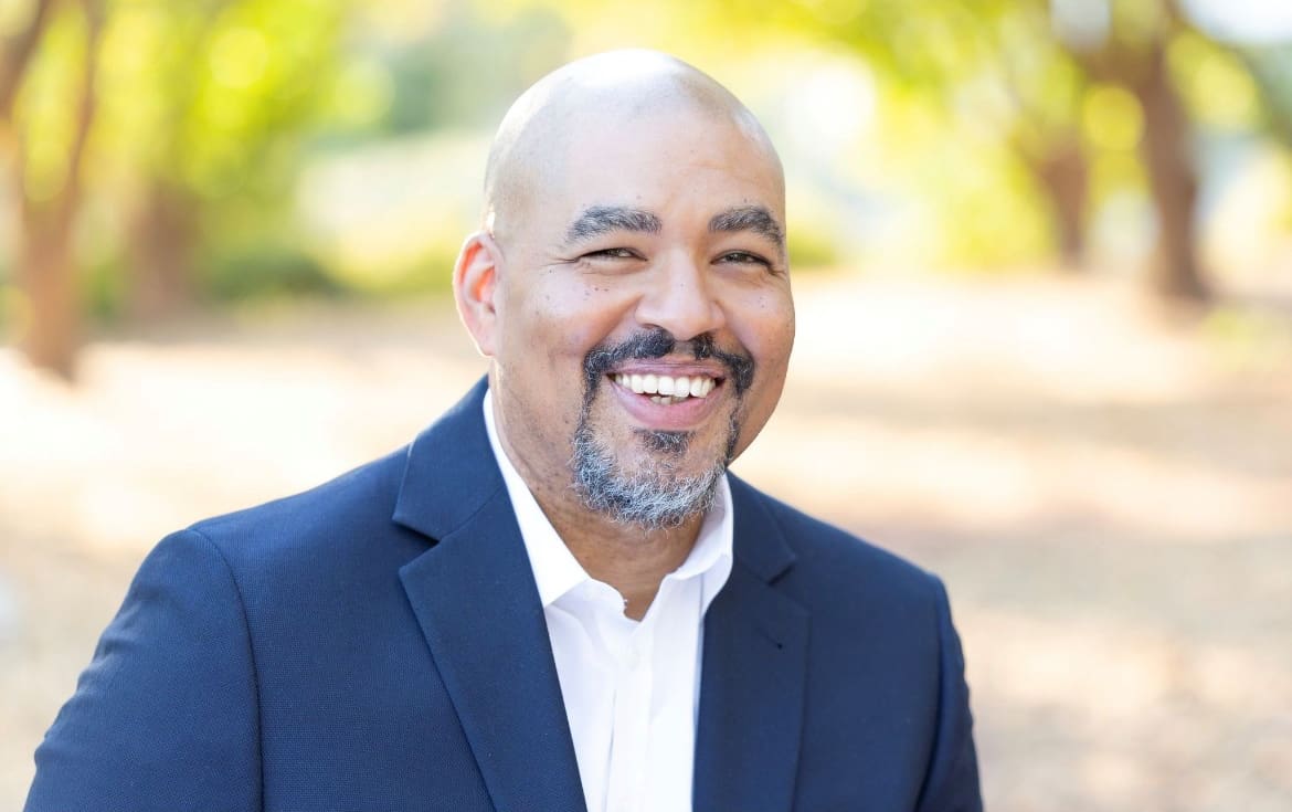 A man in a suit and tie smiling for the camera.