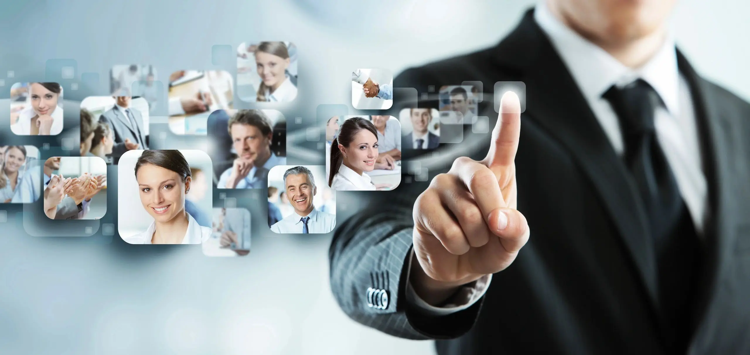 A man in suit and tie pointing to several pictures of people.